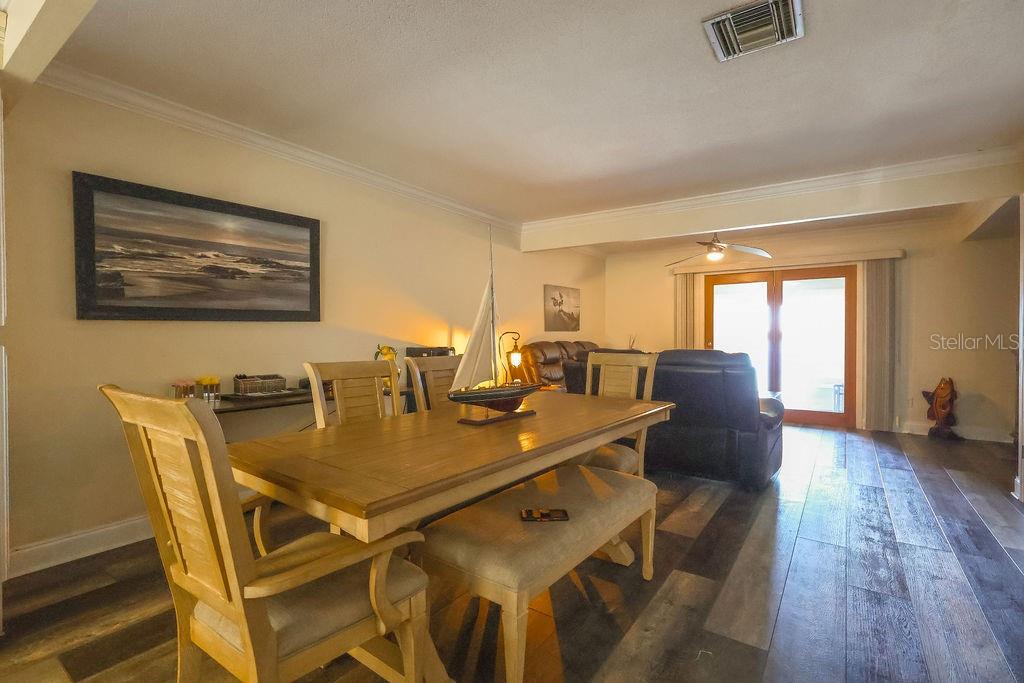 A dining area with a wooden table and chairs leads into a living room space — 11001 SE SUNSET HARBOR ROAD UNIT B10, SUMMERFIELD, FL