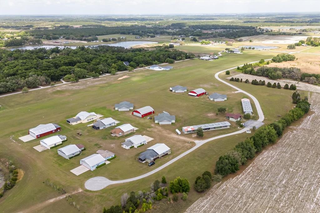 An aerial view shows a residential airpark with houses, hangars, and a grass runway — GRASS ROOTS ROAD Lot #11, GROVELAND, FL