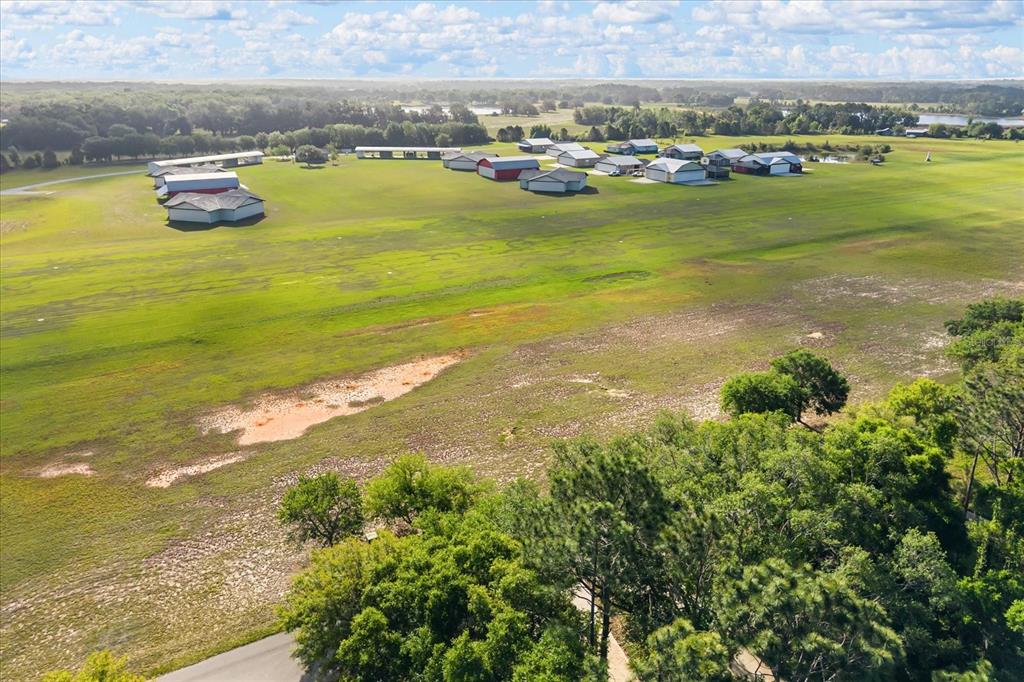 An aerial view shows a large grassy field with several hangars and a small runway — GRASS ROOTS ROAD Lot #11, GROVELAND, FL