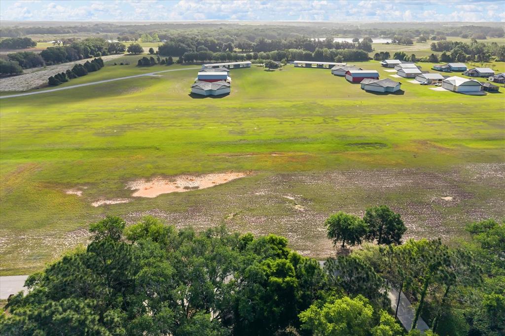 An aerial view shows a large grassy field with several residential buildings and hangars — GRASS ROOTS ROAD Lot #11, GROVELAND, FL