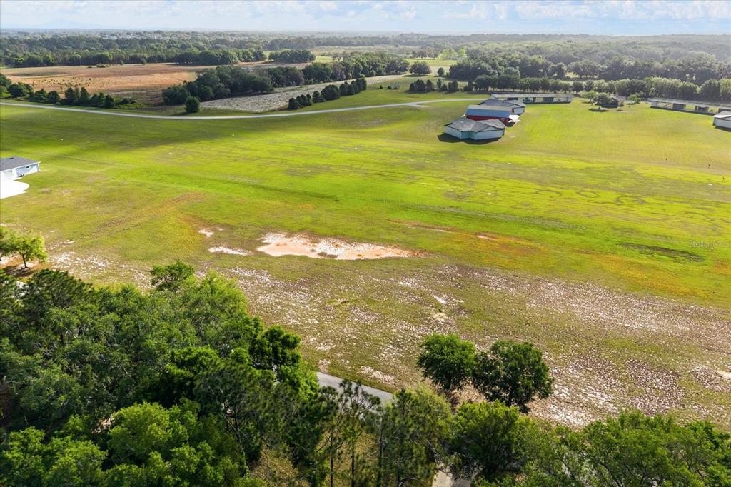 An aerial view shows a large, grassy field with a few buildings and trees — GRASS ROOTS ROAD Lot #11, GROVELAND, FL