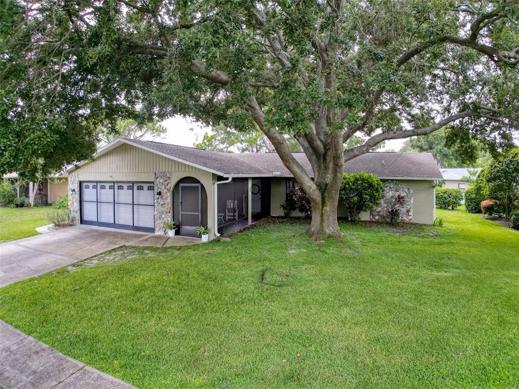 A single-story house with a garage, stone accents, and a large tree in the yard — 3711 ERIN BROOK DR, NEW PORT RICHEY, FL
