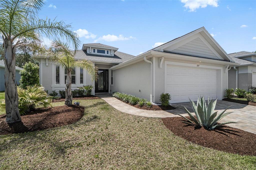 A single-story house with a white garage, palm trees, and a paved walkway — 209 HAWTHORN AVENUE, PALM COAST, FL