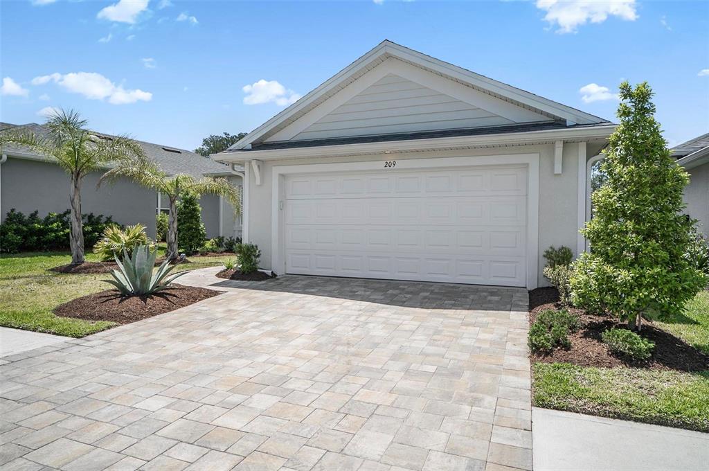 A single-story house exterior features a two-car garage, a paved driveway, and landscaped front yard — 209 HAWTHORN AVENUE, PALM COAST, FL
