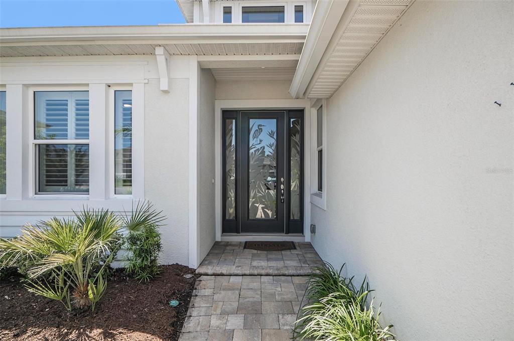 A front entryway features a dark door with glass panels and a stone paver walkway — 209 HAWTHORN AVENUE, PALM COAST, FL
