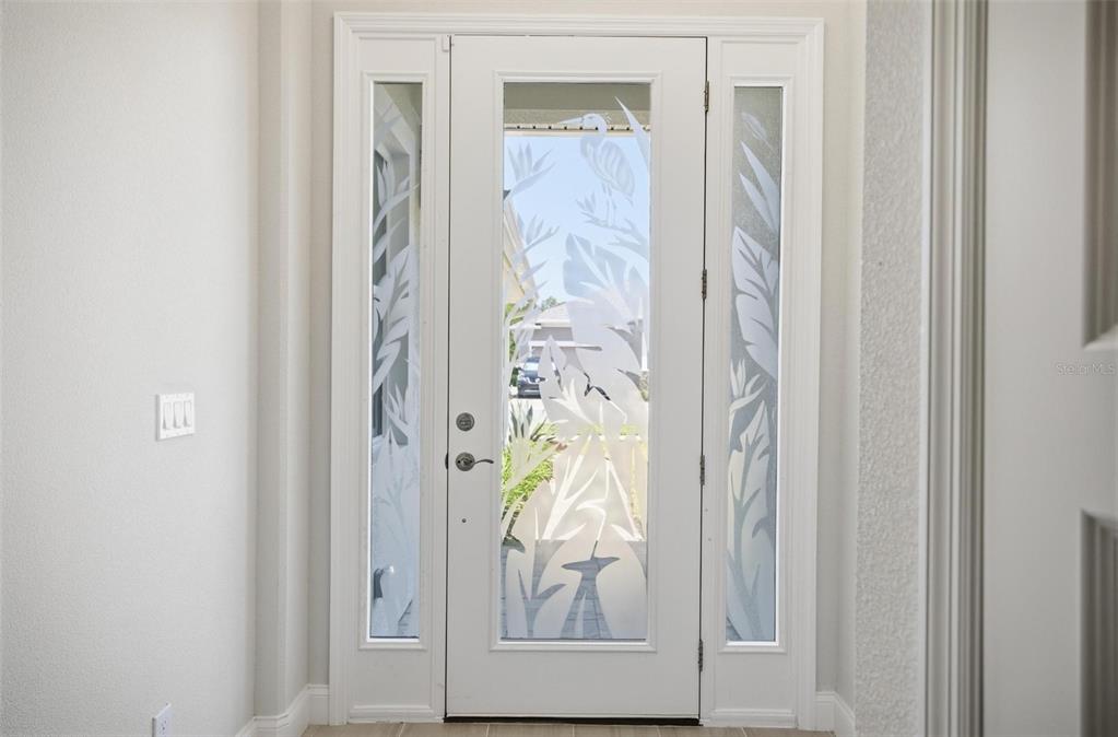 A white front door with decorative frosted glass panels and matching sidelights in an entryway — 209 HAWTHORN AVENUE, PALM COAST, FL