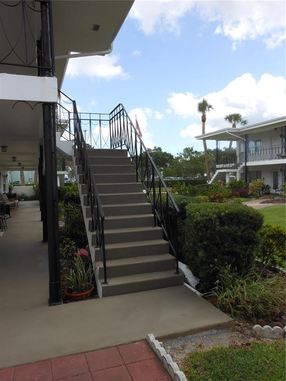 An exterior view of a concrete staircase with black metal railings leading to an upper level — 138 36TH AVENUE N UNIT 206W, ST PETERSBURG, FL