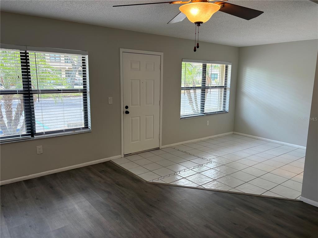 A room with a white front door, tile flooring near the entrance, and wood-look flooring — 515 30TH AVENUE W UNIT H108, BRADENTON, FL
