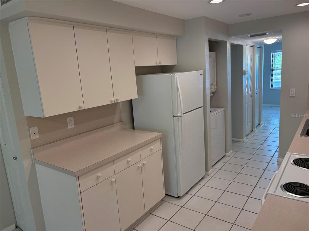 A kitchen features white cabinets, laminate countertops, a white refrigerator, and tiled flooring — 515 30TH AVENUE W UNIT H108, BRADENTON, FL