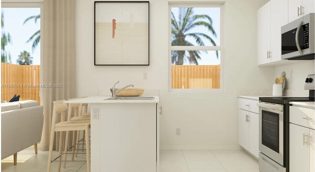 A modern kitchen features white cabinetry, stainless steel appliances, a central island, and a window — 12629 NW 23rd Pl, Miami FL 33167, MIAMI, FL