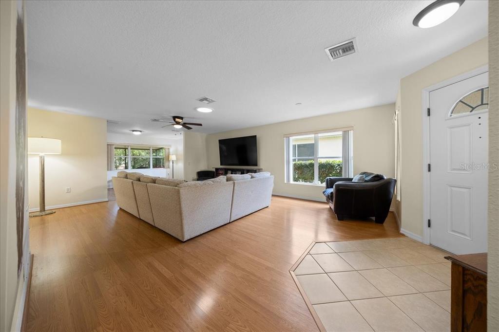 A living room features light wood flooring, a large sectional sofa, and a television — 9082 SW 102ND CIRCLE, OCALA, FL