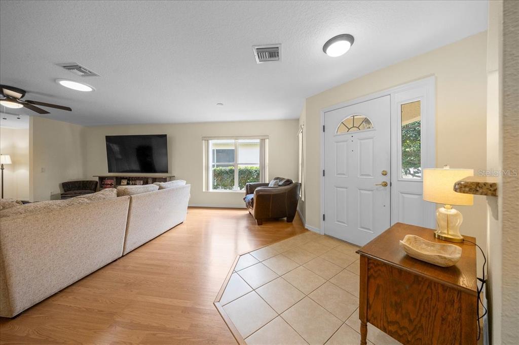 A living room with wood flooring, a tiled entryway, and a white front door — 9082 SW 102ND CIRCLE, OCALA, FL