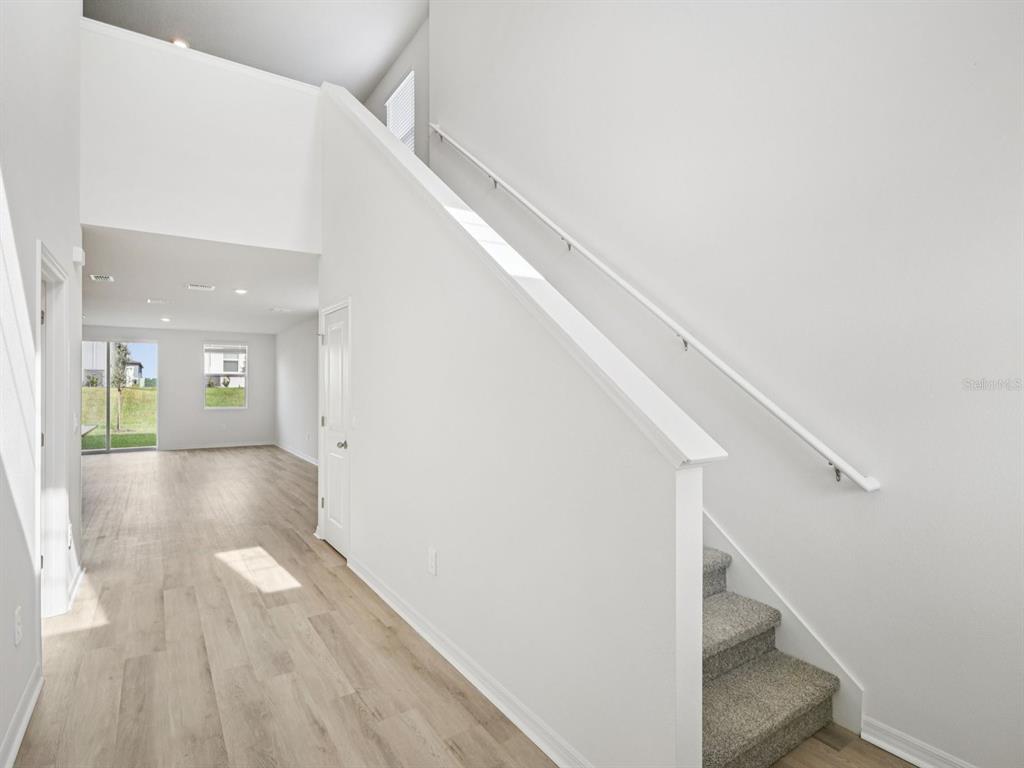 A view of a staircase with carpeted steps and a white railing next to a hallway — 1445 BREKEY WAY, ZEPHYRHILLS, FL