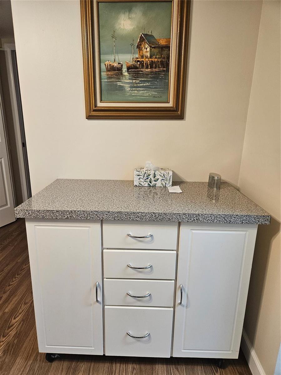 A white kitchen island with a granite countertop sits below a framed landscape painting — 82 Tilford D # 82, Deerfield Beach FL 33442, DEERFIELD BEACH, FL