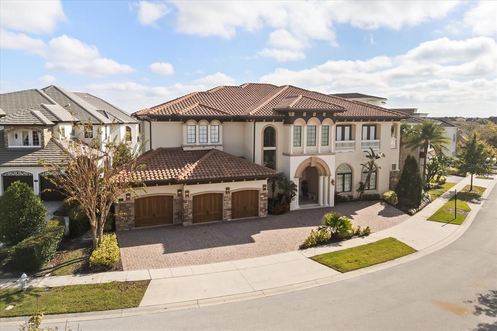 An aerial view of a large, two-story Mediterranean-style house with a three-car garage — 7840 PALMILLA COURT, REUNION, FL
