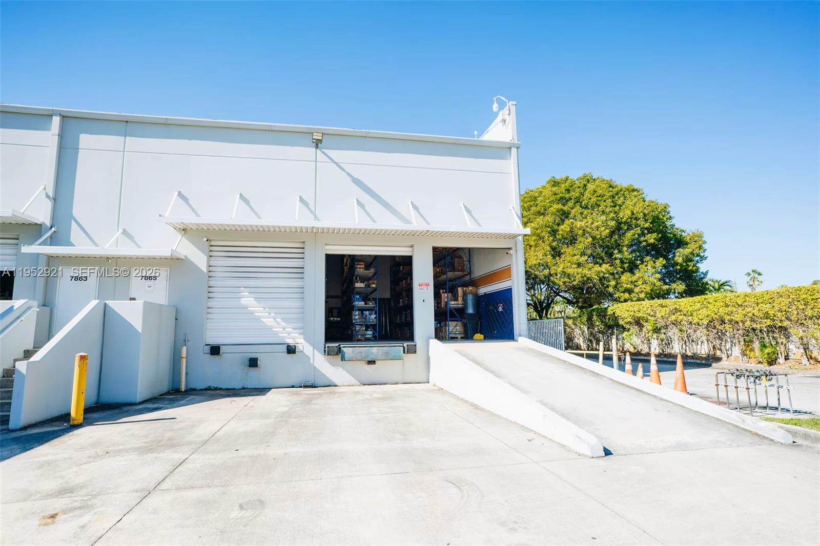 The exterior of a commercial warehouse building features a loading dock, ramp, and roll-up door — 7865 NW 46th St # 8, Doral FL 33166, DORAL, FL
