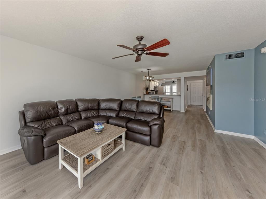 A living room features a brown leather sectional, a wooden coffee table, and light flooring — 210 SILVER LAKE DRIVE UNIT 102, VENICE, FL