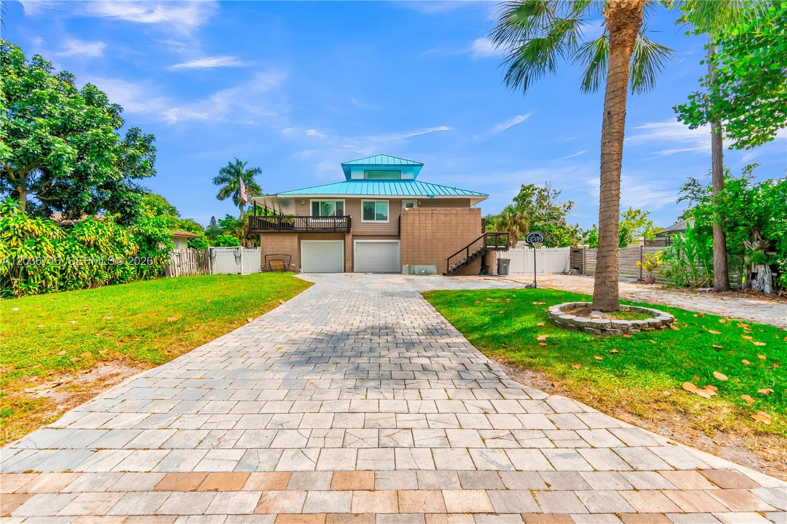 A two-story house with a blue metal roof, beige siding, and a paved driveway — 5049 Cleveland Rd, Delray Beach FL 33484, DELRAY BEACH, FL