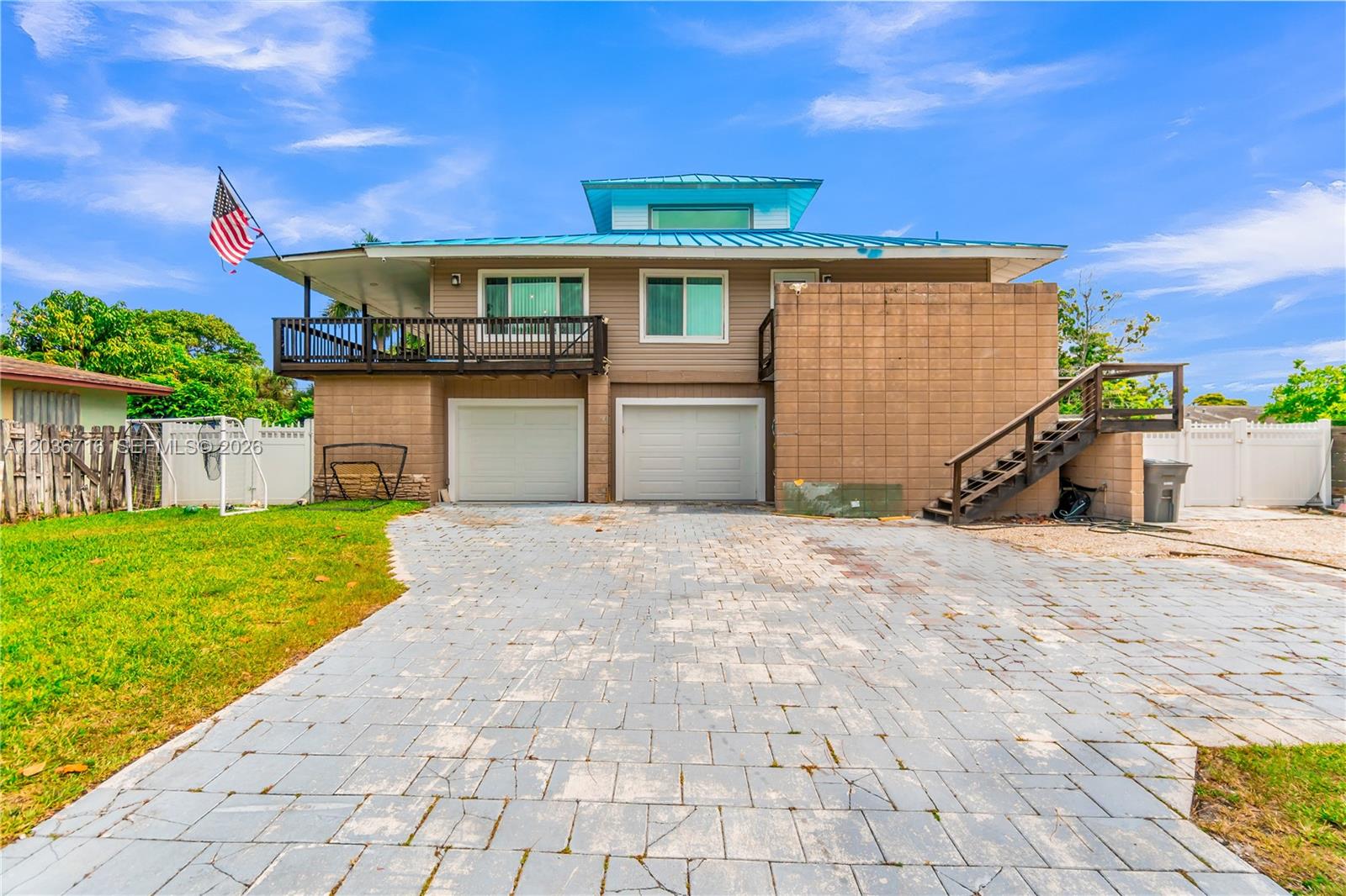 A two-story house with a blue metal roof, two garage doors, and an exterior staircase — 5049 Cleveland Rd, Delray Beach FL 33484, DELRAY BEACH, FL