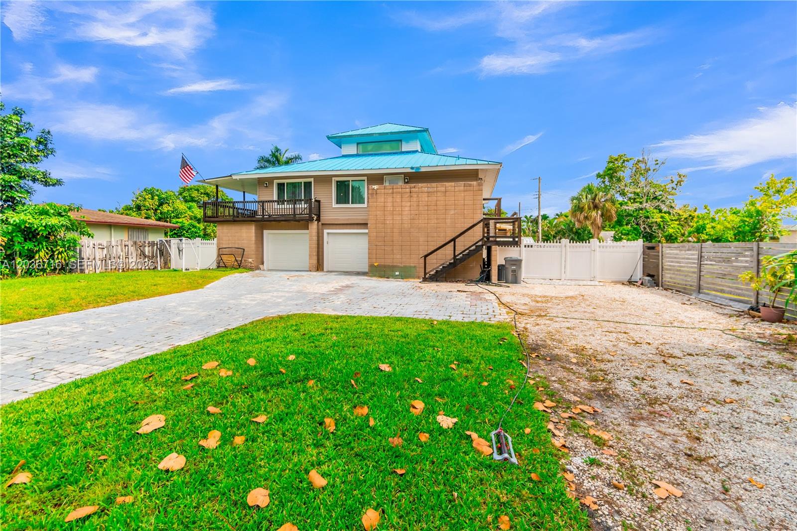 A two-story house with a blue metal roof, garage doors, and an exterior staircase — 5049 Cleveland Rd, Delray Beach FL 33484, DELRAY BEACH, FL