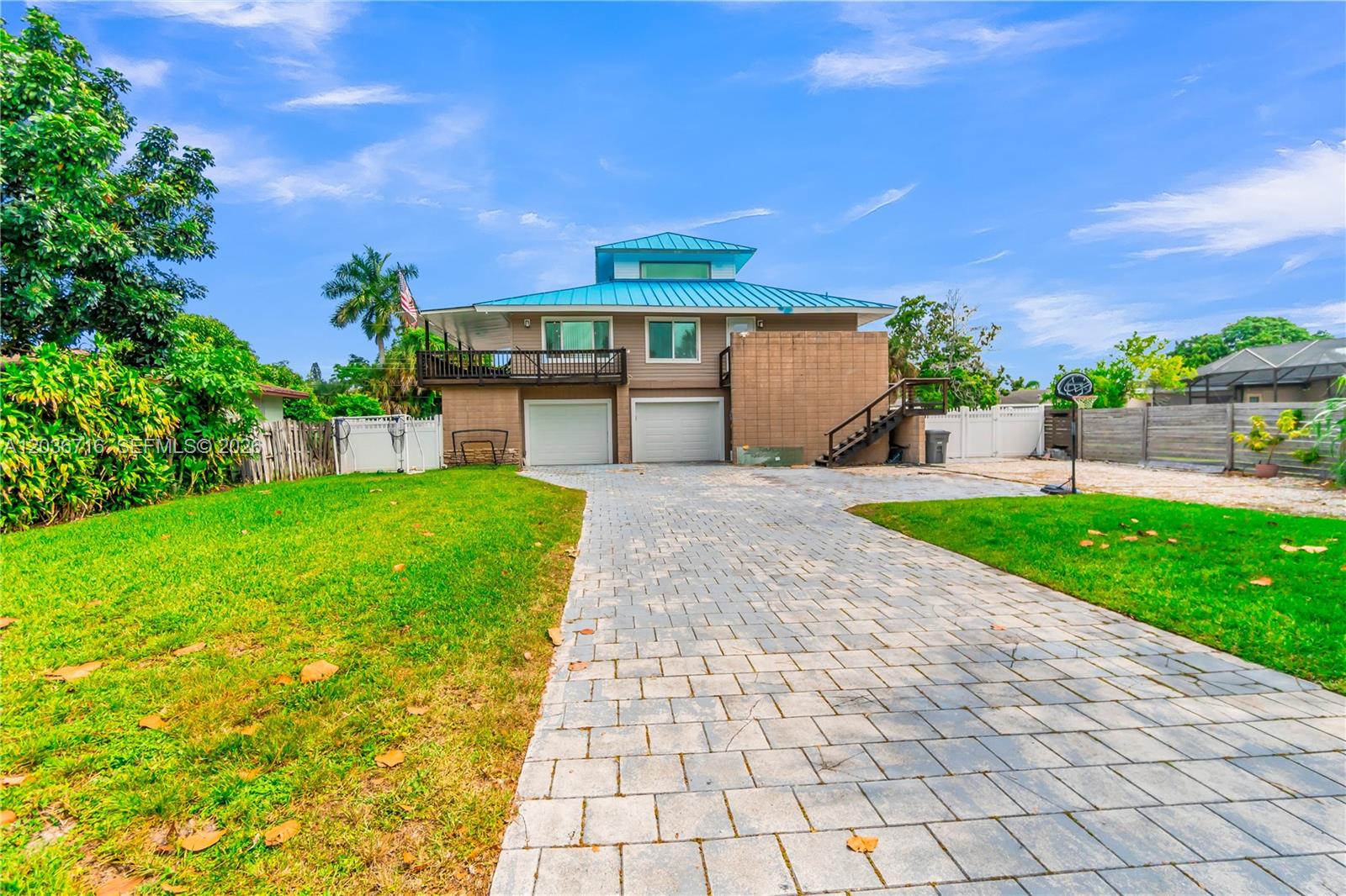 A two-story house with a blue metal roof, a paved driveway, and an exterior staircase — 5049 Cleveland Rd, Delray Beach FL 33484, DELRAY BEACH, FL
