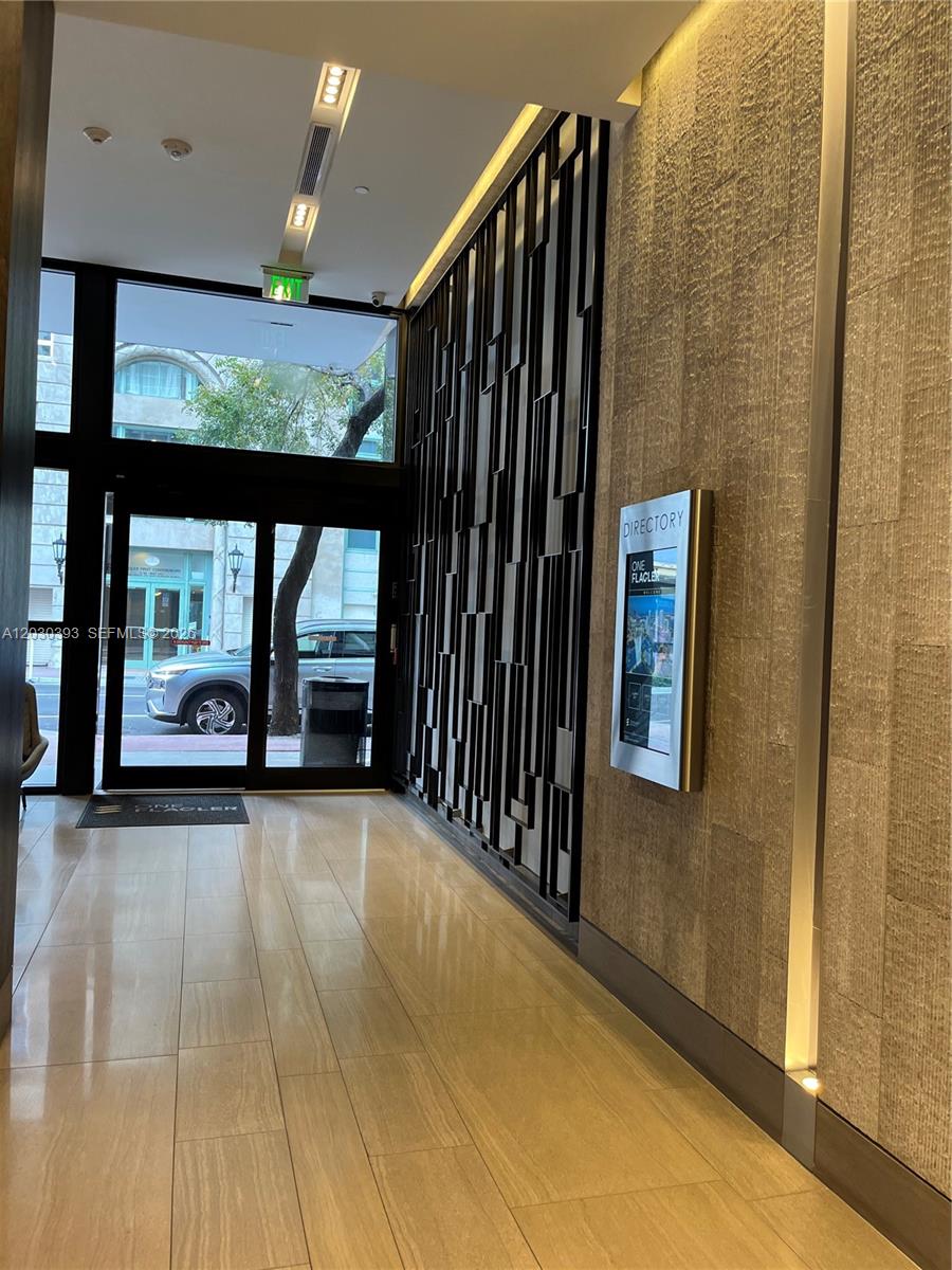 A modern building lobby features a stone wall, a directory screen, and glass entry doors — 14 NE 1st Ave # 1210, Miami FL 33132, MIAMI, FL