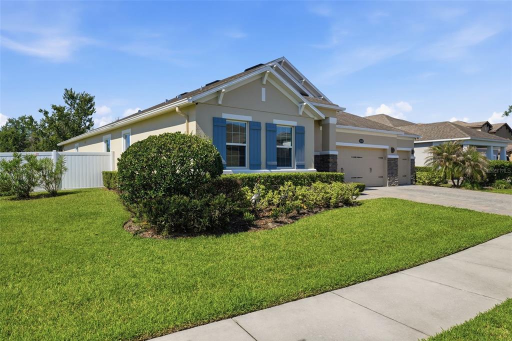 A tan single-story house with blue shutters, a two-car garage, and a manicured front lawn — 12249 NORTHOVER LOOP, ORLANDO, FL