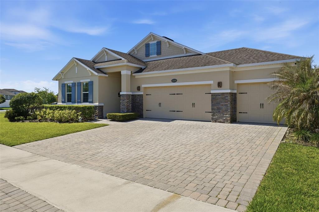 A single-story house with a three-car garage, stone accents, and a paved driveway — 12249 NORTHOVER LOOP, ORLANDO, FL
