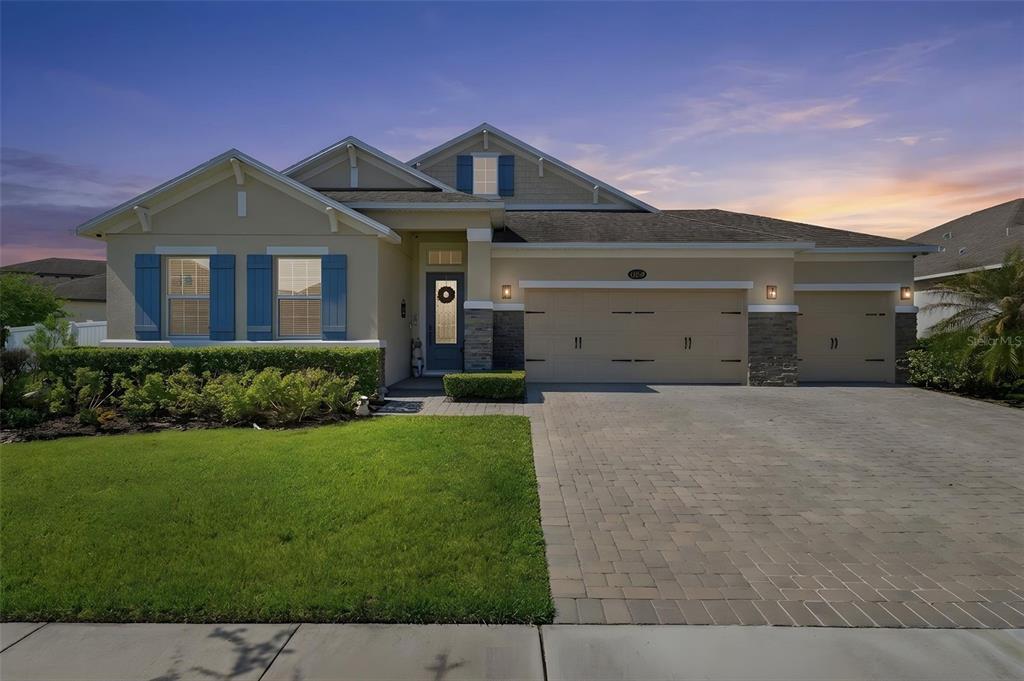 A single-story suburban house features a tan stucco exterior, blue shutters, and a paved driveway — 12249 NORTHOVER LOOP, ORLANDO, FL