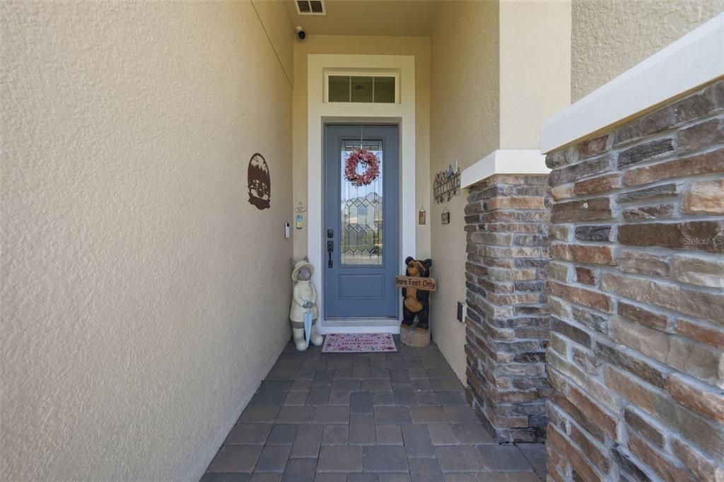 A covered entryway features a blue front door, stone accents, and decorative statues — 12249 NORTHOVER LOOP, ORLANDO, FL