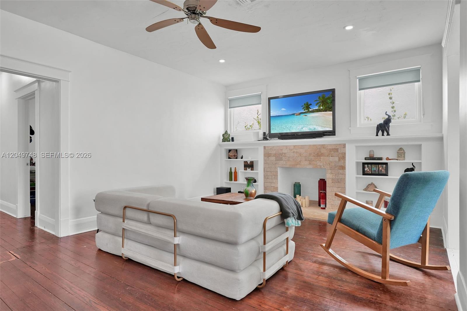 A living room features a white sofa, a blue rocking chair, and a brick fireplace — 1933 Madison St, Hollywood FL 33020, HOLLYWOOD, FL