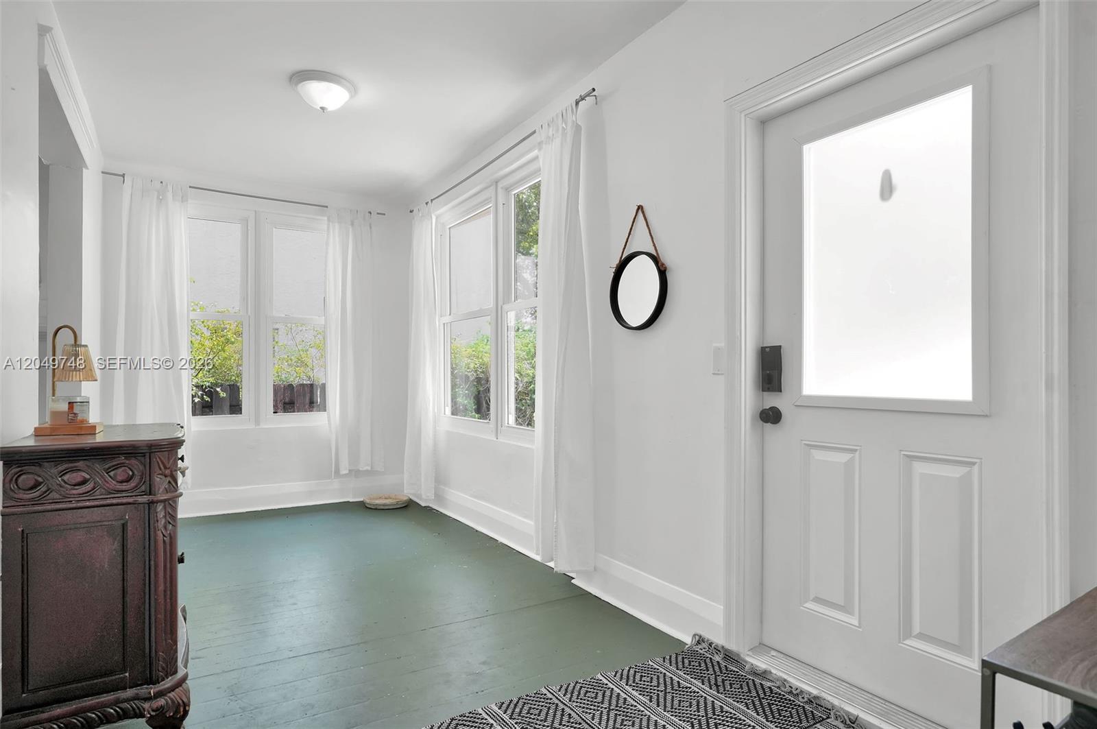 A sunroom features white walls, green painted wood floors, large windows, and a white door — 1933 Madison St, Hollywood FL 33020, HOLLYWOOD, FL