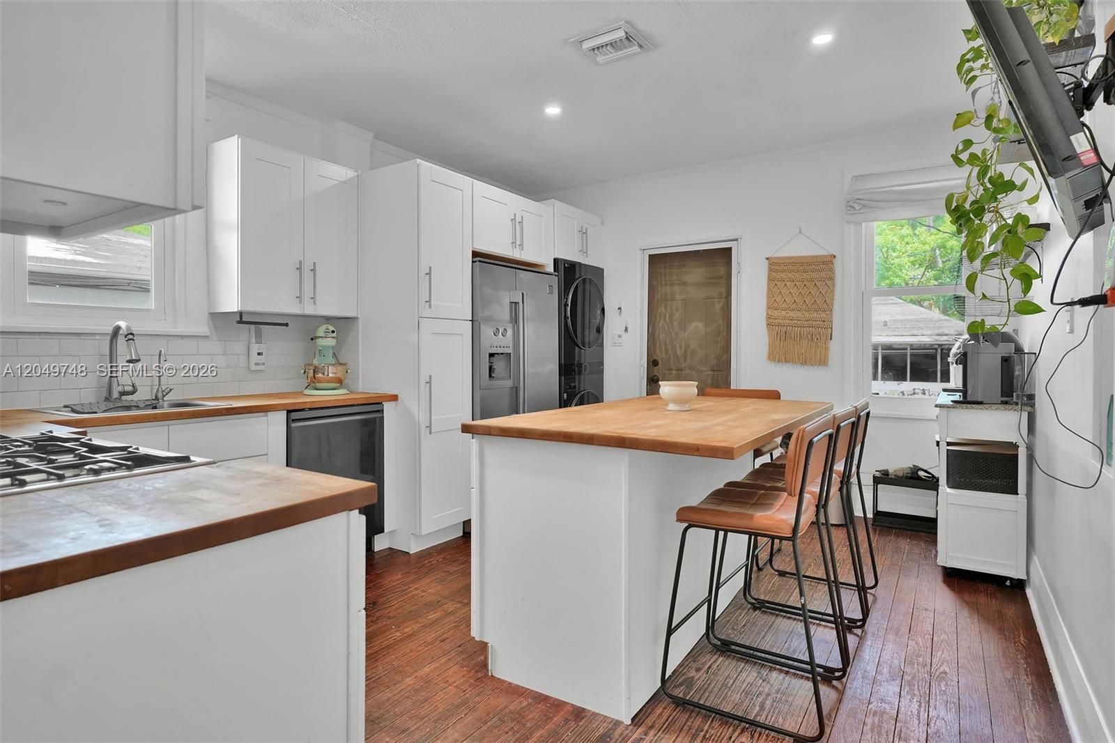 A kitchen features white cabinets, wood countertops, a central island, and stainless steel appliances — 1933 Madison St, Hollywood FL 33020, HOLLYWOOD, FL