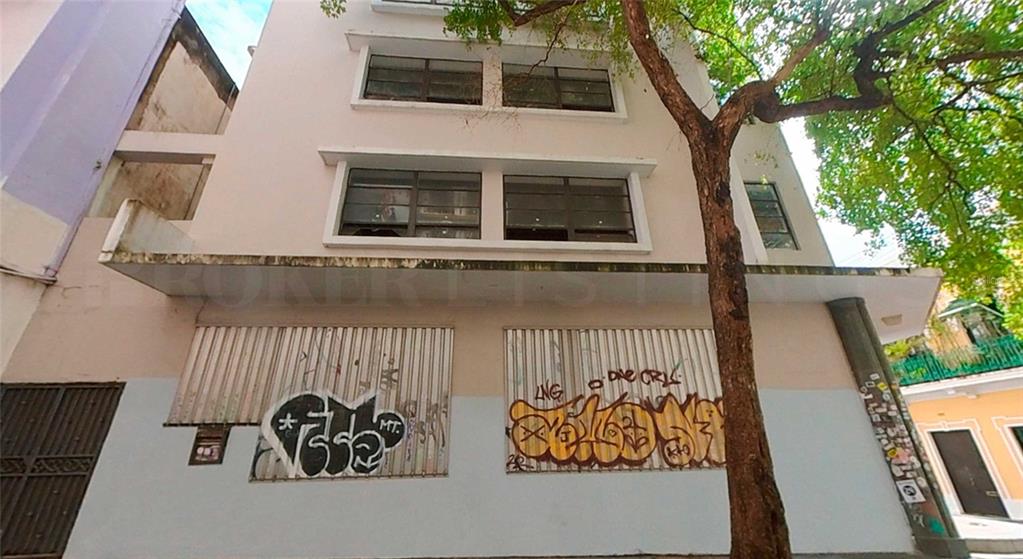 A low-angle view of a multi-story building exterior with graffiti-covered metal shutters on the ground floor — 201 TETUAN STREET, SAN JUAN, PR