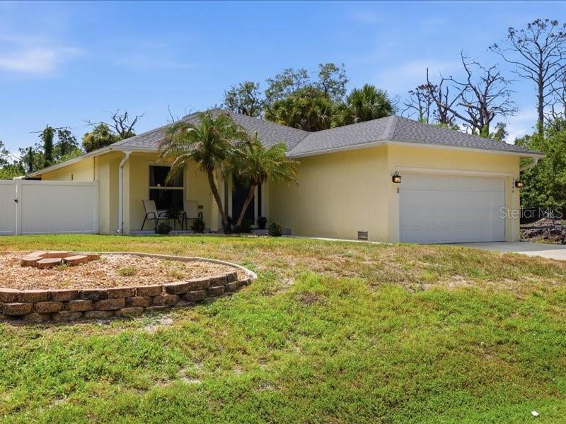 A single-story yellow house with a two-car garage and a small front yard — 1006 RHINELANDER STREET, PORT CHARLOTTE, FL