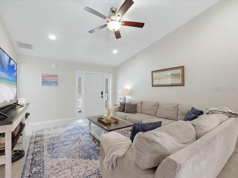 A living room features a ceiling fan, a beige sectional sofa, and a patterned area rug — 1006 RHINELANDER STREET, PORT CHARLOTTE, FL