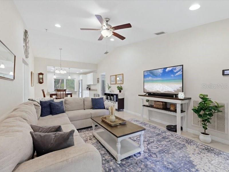 A living room with a sectional sofa, coffee table, television, and an open kitchen area — 1006 RHINELANDER STREET, PORT CHARLOTTE, FL