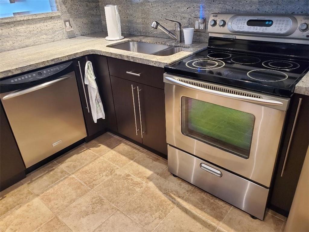 A kitchen features dark wood cabinets, granite countertops, stainless steel appliances, and tiled flooring — 3000 S Course Drive # 505, Pompano Beach FL 33069, POMPANO BEACH, FL