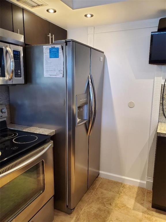 A stainless steel refrigerator stands next to a kitchen stove and dark wood cabinets — 3000 S Course Drive # 505, Pompano Beach FL 33069, POMPANO BEACH, FL