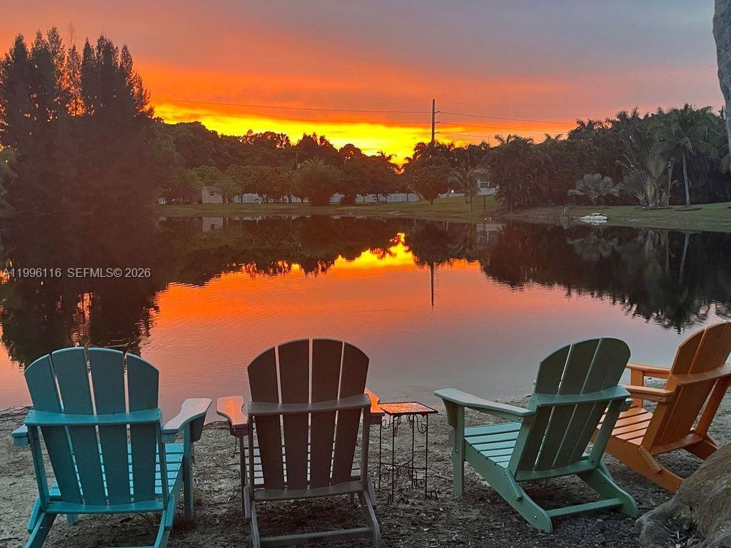 Four Adirondack chairs face a pond at sunset with trees in the background — 18901 SW 63rd St, Southwest Ranches FL 33332, SOUTHWEST RANCHES, FL
