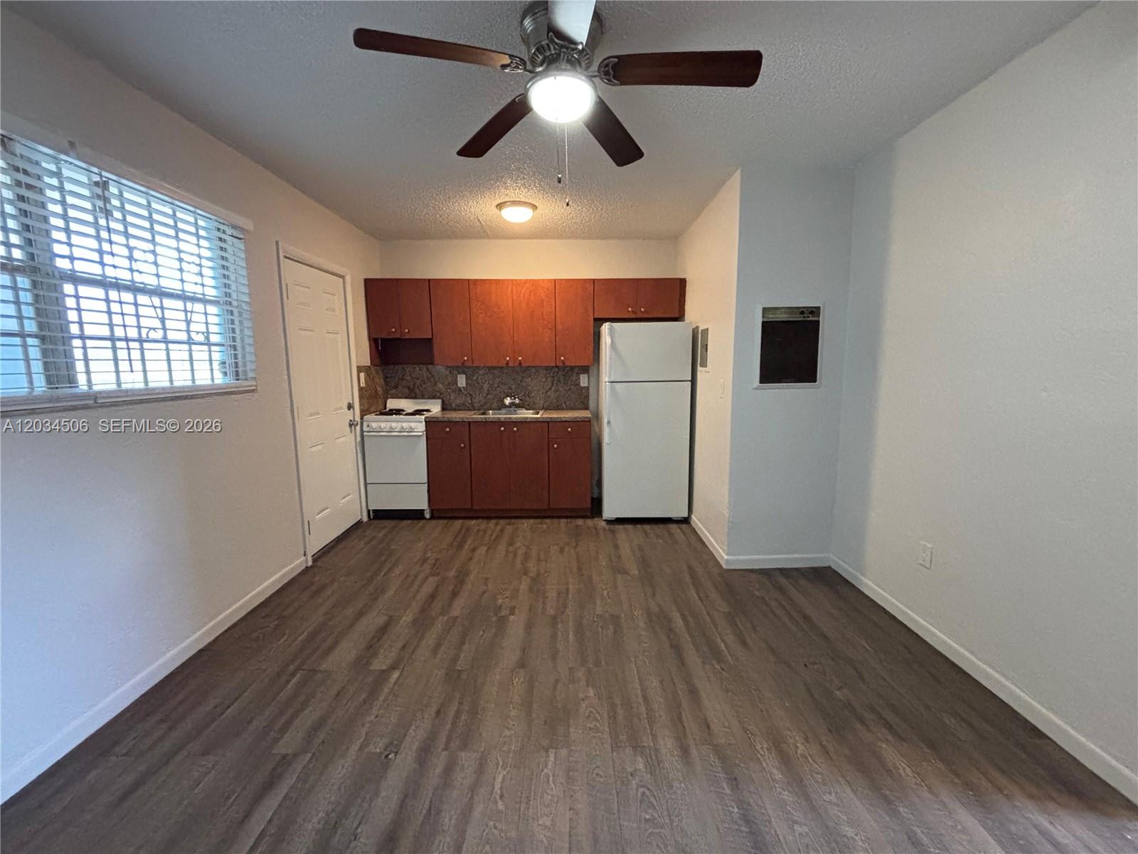 This kitchen features wood cabinets, a white stove, a refrigerator, and wood-look flooring — 14120 NW 24th Ct # 303, Opa-Locka FL 33054, OPA-LOCKA, FL