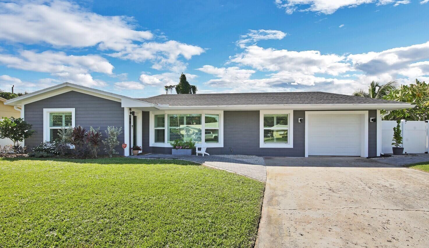 A single-story house with gray horizontal siding, a white garage door, and a paved driveway — 68 Azalea Circle, Jupiter FL 33469, JUPITER, FL