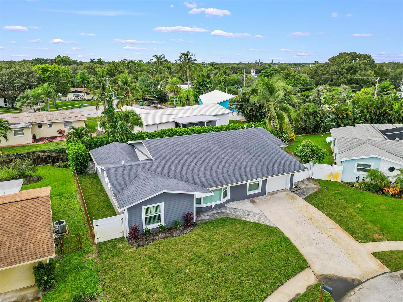 An aerial view shows a gray single-story house with a dark shingled roof and driveway — 68 Azalea Circle, Jupiter FL 33469, JUPITER, FL