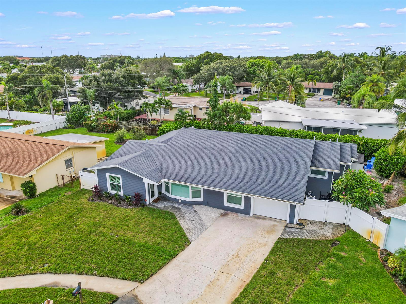 An aerial view shows a gray single-story house with a shingled roof and concrete driveway — 68 Azalea Circle, Jupiter FL 33469, JUPITER, FL