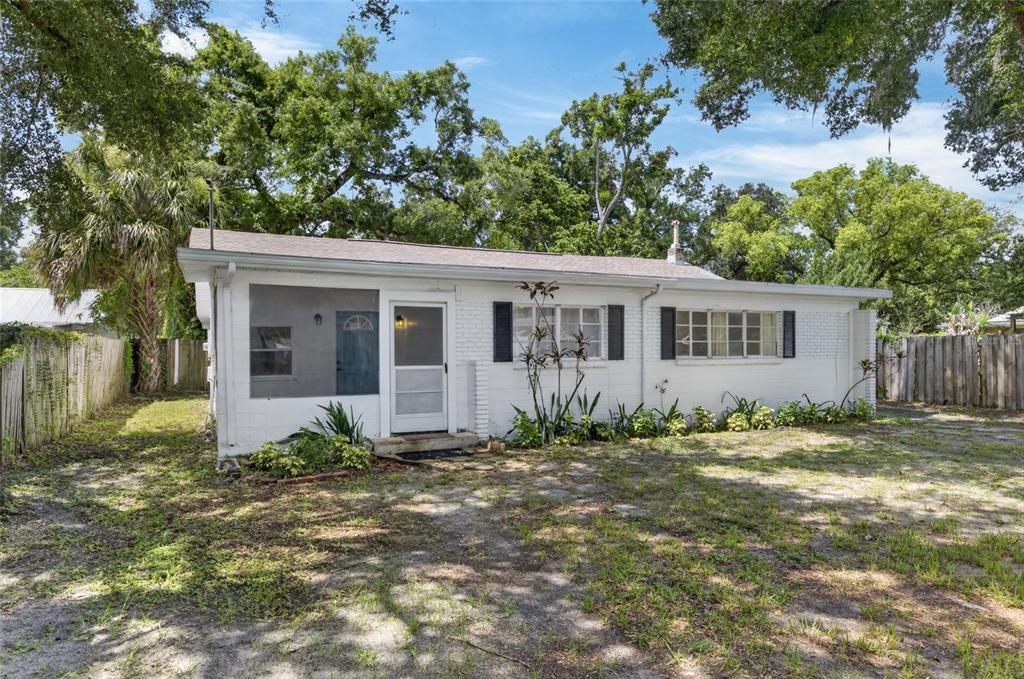 A white, single-story house with a screened-in porch and black shutters sits on a lot — 1005 E FLORA STREET, TAMPA, FL