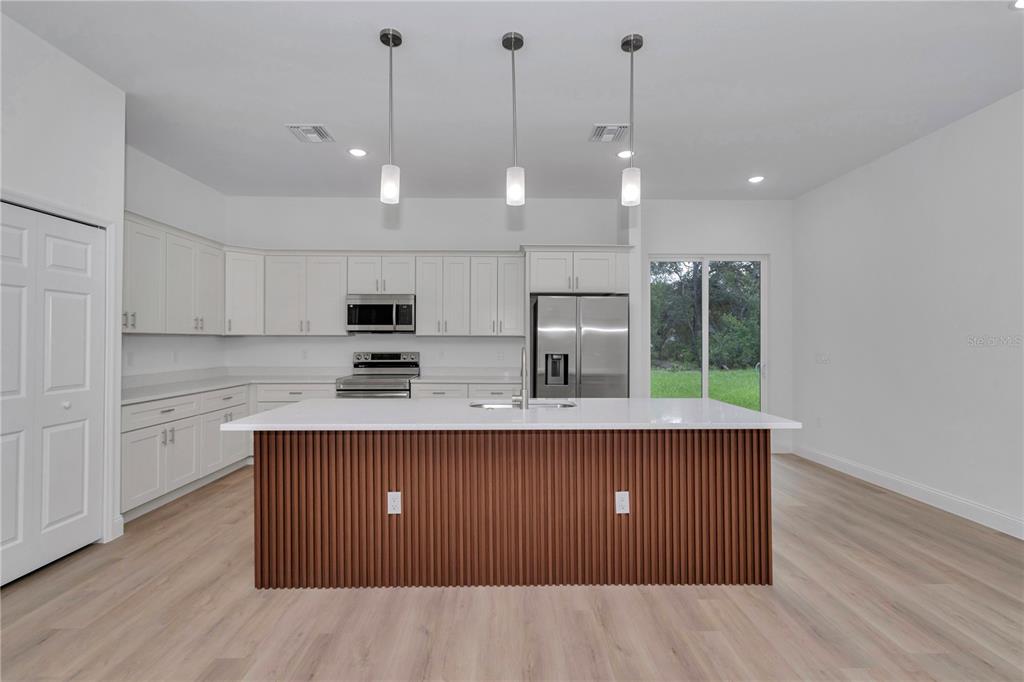 A modern kitchen features white cabinetry, a wood-slatted island, and stainless steel appliances — 6202 N MARINER TERRACE, CITRUS SPRINGS, FL