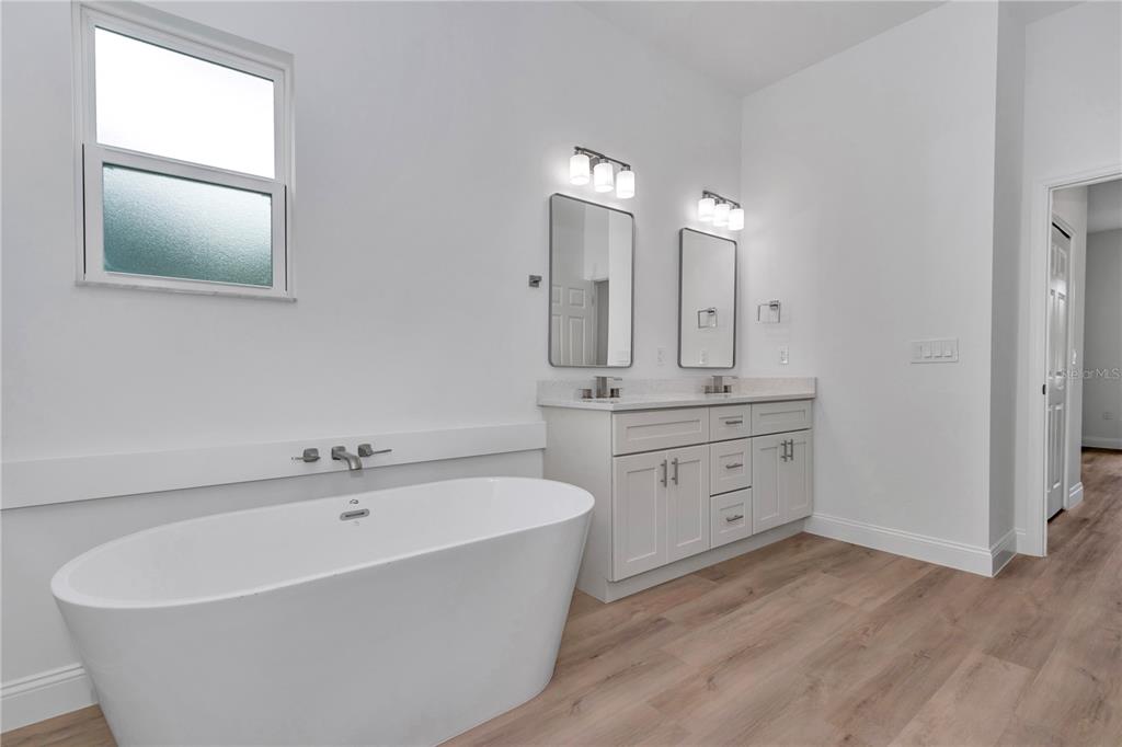 A bathroom features a freestanding tub, a double vanity with mirrors, and light wood flooring — 6202 N MARINER TERRACE, CITRUS SPRINGS, FL