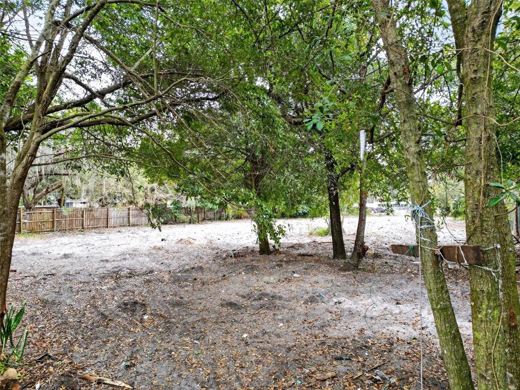 A vacant, sandy lot with several trees and a wooden fence in the background — 6935 TURQUOISE LANE, ORLANDO, FL