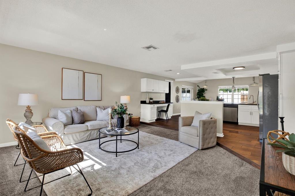 A living room with a sofa, two rattan chairs, and an adjacent kitchen area — 10898 119TH STREET N, SEMINOLE, FL