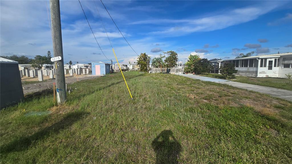 A grassy vacant lot sits between two mobile homes under a blue sky — 1399 FLAMINGO DRIVE, ENGLEWOOD, FL